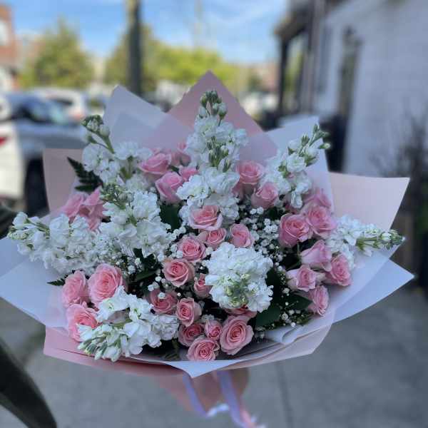 Bouquet of pink roses and white flowers wrapped in pastel paper