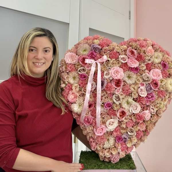 Heart-shaped pink floral arrangement with a ribbon bow