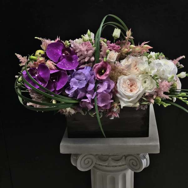 Mixed floral arrangement with purple orchids and white roses in a rectangular container