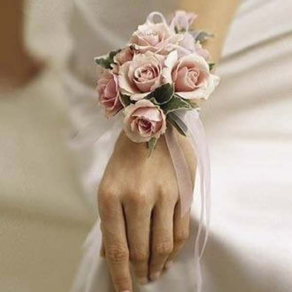 Pink rose wrist corsage with ribbon on a hand