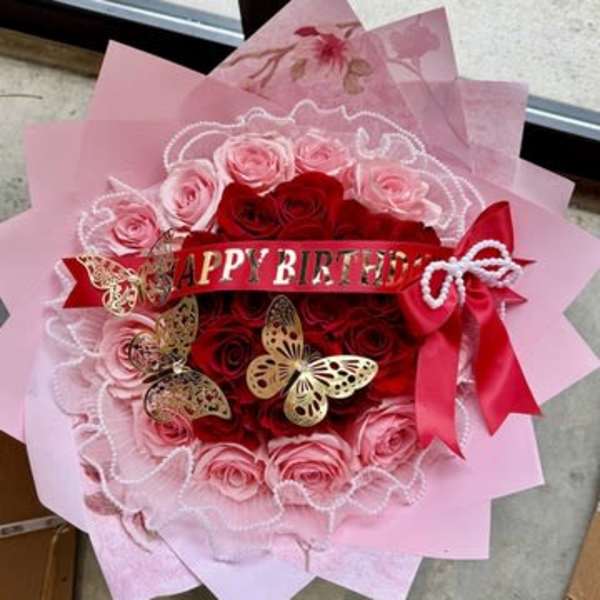 Pink and red rose bouquet with a birthday ribbon and butterfly decorations
