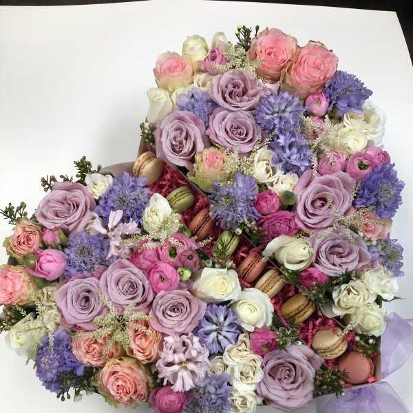Pastel bouquet of roses, lavender blooms, and macarons tied with a lilac ribbon