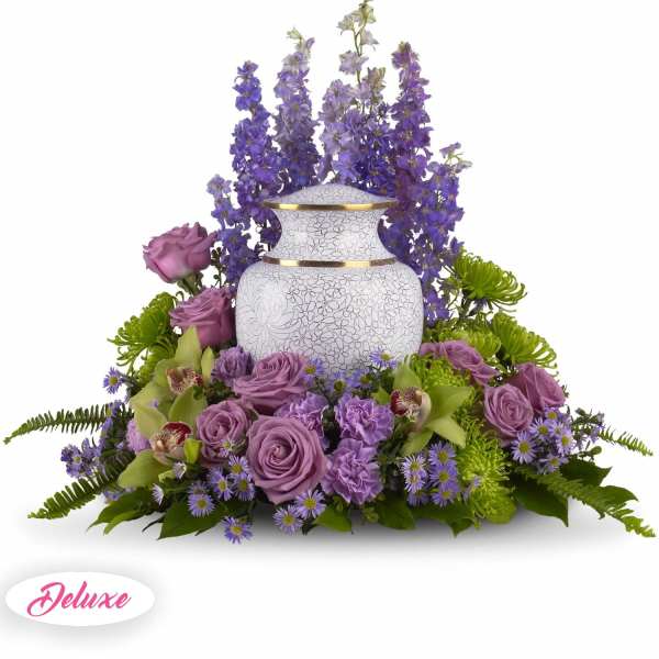 Purple floral arrangement around a white urn vase