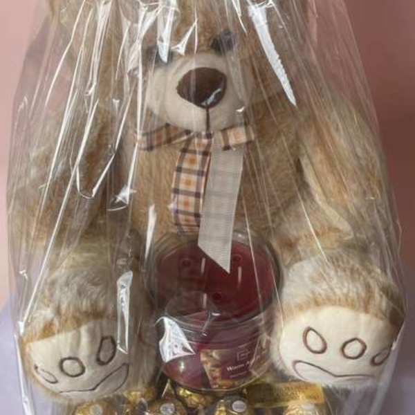 Teddy bear gift basket wrapped in clear plastic with a red bow