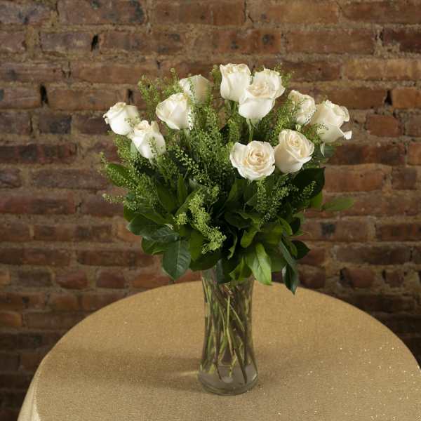 White roses in a clear glass vase on a table