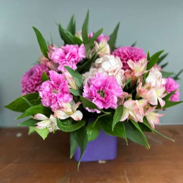 Pink carnations and pale alstroemeria in a purple vase