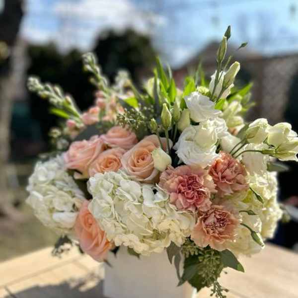 Peach roses and white hydrangeas in a white box arrangement