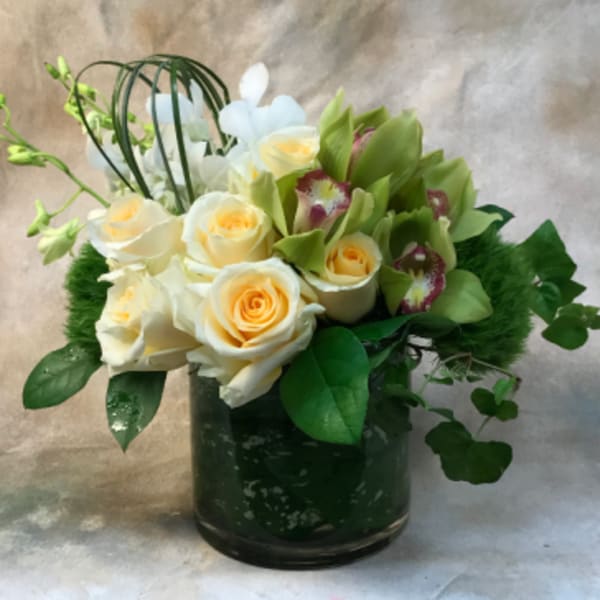 Bouquet of cream roses and green orchids in a dark glass vase