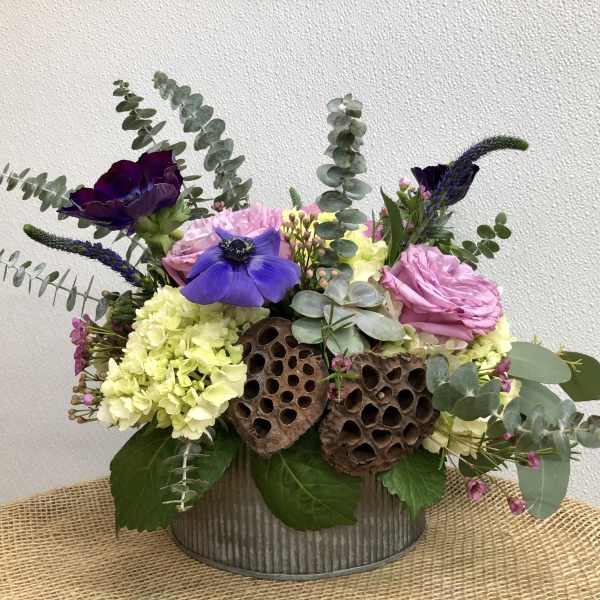 Mixed bouquet in a metal container with pink, purple, and yellow blooms