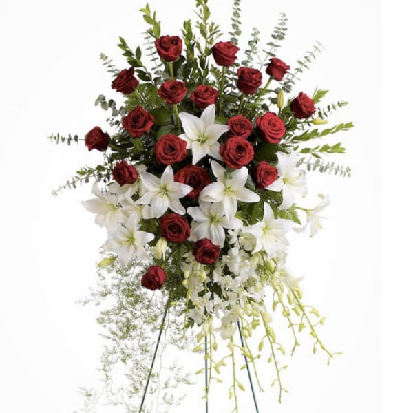 Standing floral spray with red roses and white lilies on a metal easel