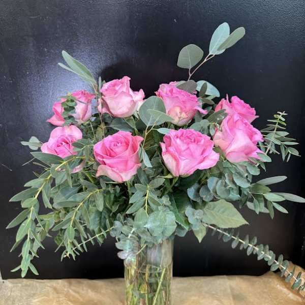 Pink roses in a clear glass vase with eucalyptus