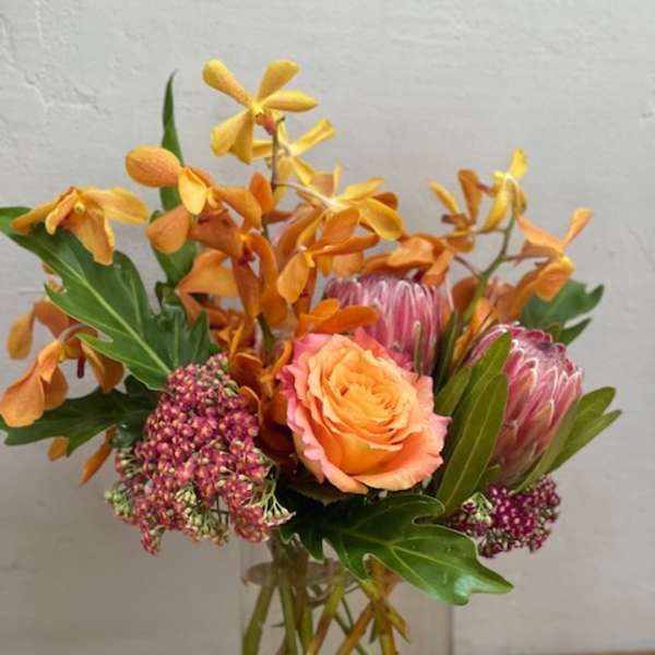 Orange and pink floral arrangement in a clear glass vase