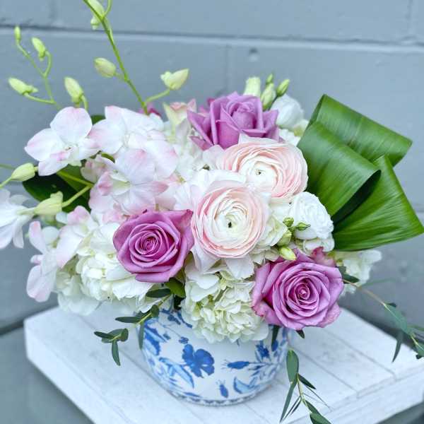 Pink and white flower arrangement in a blue-and-white ceramic vase