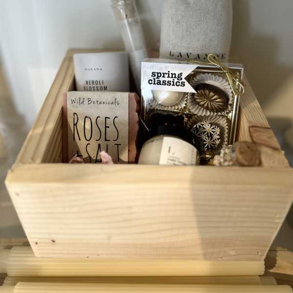 Gift basket with soaps, candles, and chocolates in a wooden crate