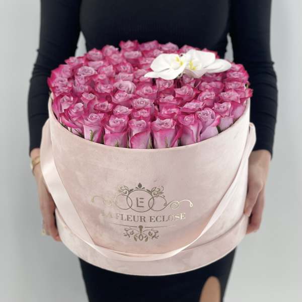 Round box of pink roses with a white orchid accent