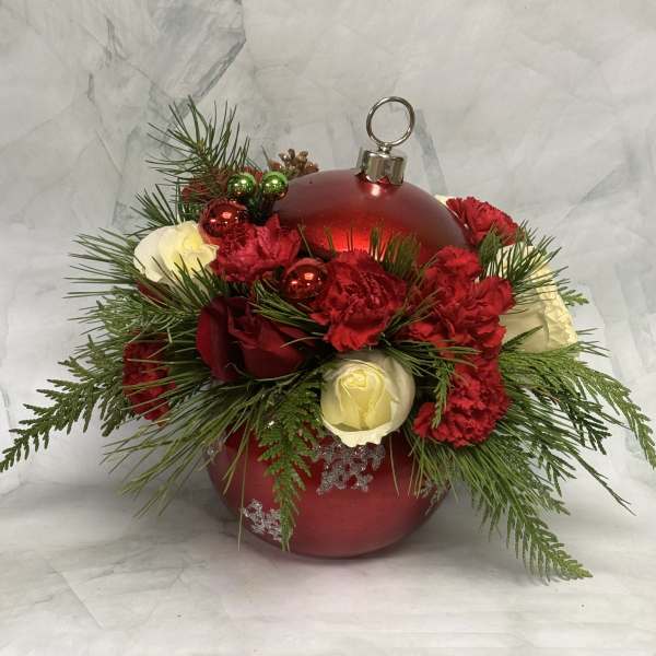 Red ornament with red and white flowers and evergreen sprigs