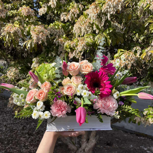 Pink and peach flower arrangement in a white box