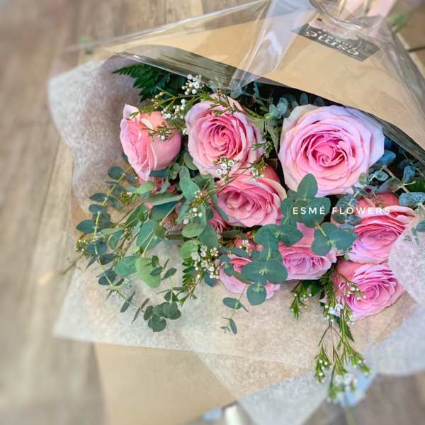 Bouquet of pink roses with eucalyptus in brown paper wrap