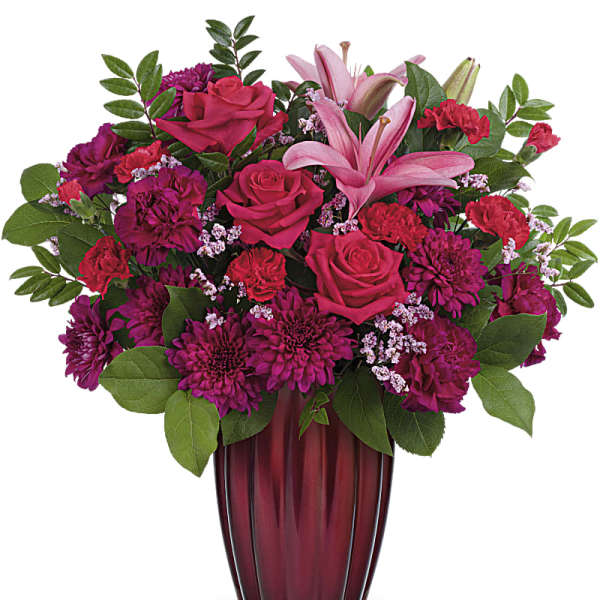 Pink and magenta flower arrangement in a red glass vase