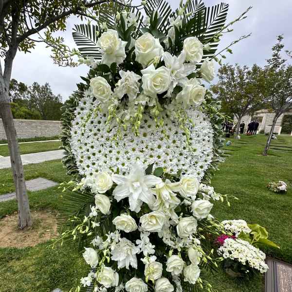 Tall white funeral spray with roses and daisies on a standing easel