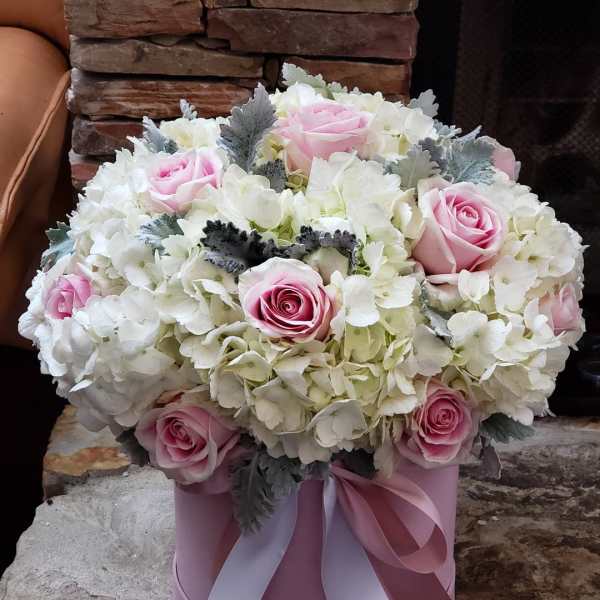Pink roses and white hydrangeas in a pink hatbox with ribbon