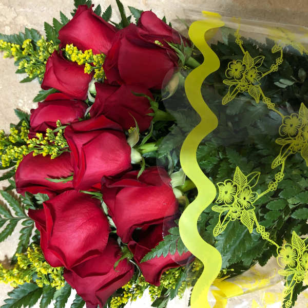 Bouquet of red roses wrapped in clear plastic with yellow ribbon