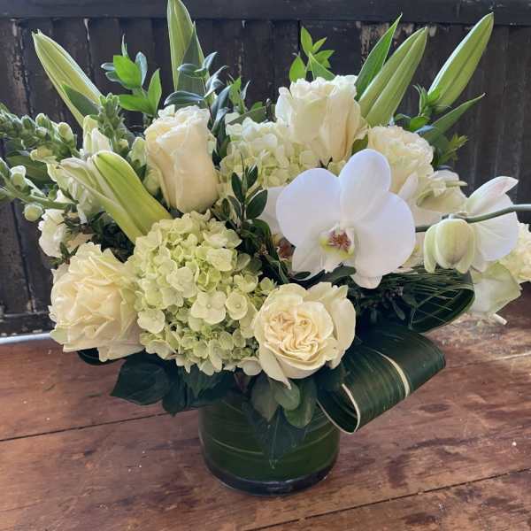 White roses and orchids arranged in a green vase