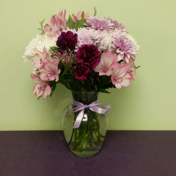 Pink and white mixed bouquet in a glass vase with a lavender ribbon