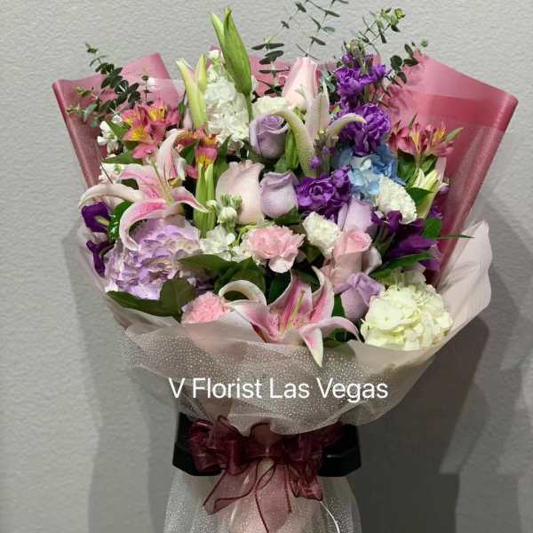Bouquet of pink, purple, and white flowers wrapped in pink paper