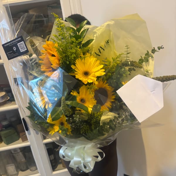 Bouquet of yellow sunflowers wrapped in clear plastic with a white ribbon