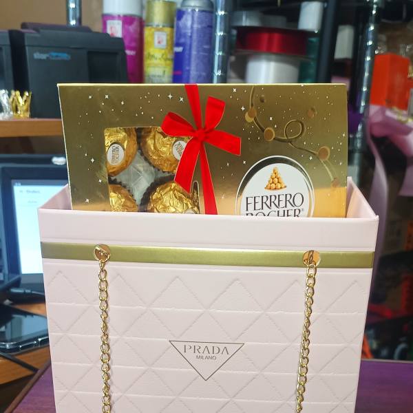 Ferrero Rocher chocolates in a Prada gift bag with a red bow