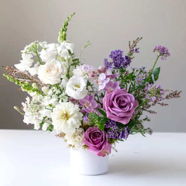 Purple and white mixed bouquet in a white vase