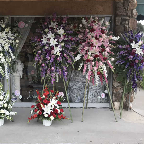 Large standing floral sprays in white, purple, pink, and red outside a storefront