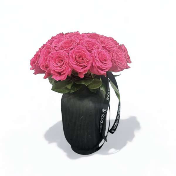 Pink rose bouquet in a black vase with a ribbon