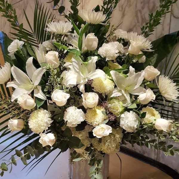 White floral arrangement with roses, lilies, and chrysanthemums in a vase