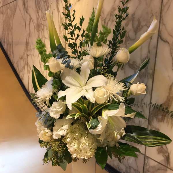 Tall white floral arrangement in a pedestal vase