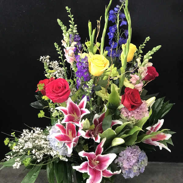 Tall mixed bouquet with roses, lilies, and hydrangeas in a glass vase