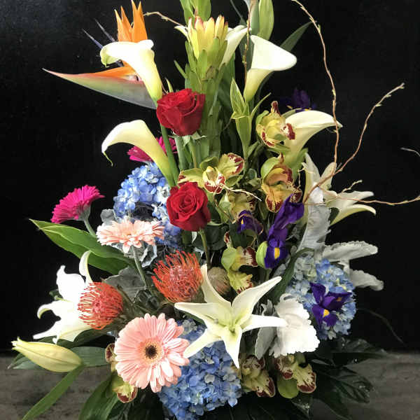 Tall tropical flower arrangement with lilies, roses, and orchids