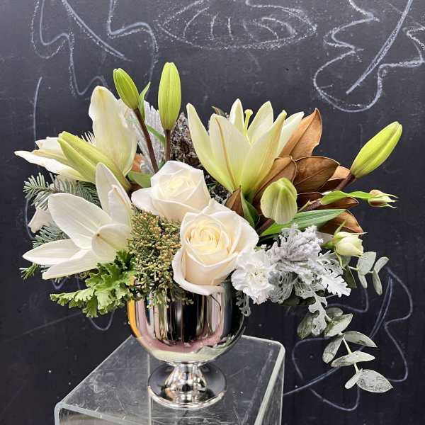 White lilies and roses arranged in a silver vase
