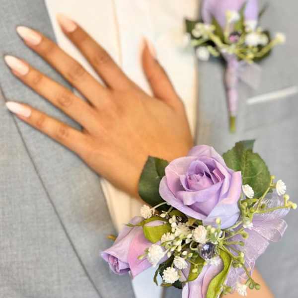 Lavender rose corsage with small white flowers on a wrist