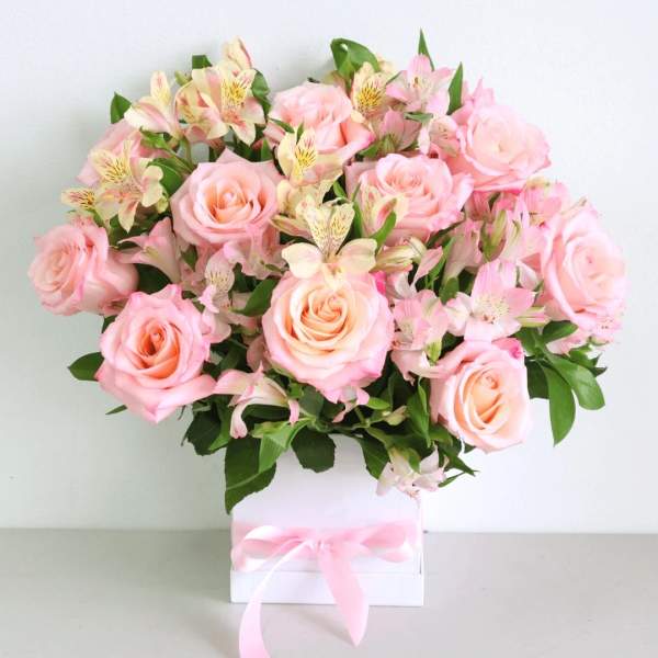 Pink roses and pale alstroemeria in a white box tied with a pink ribbon