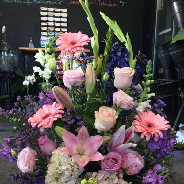 Large mixed flower basket with pink lilies, roses, gerbera daisies, and purple blooms