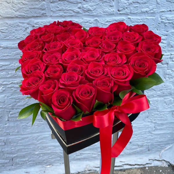 Heart-shaped bouquet of red roses in a black box with a red ribbon