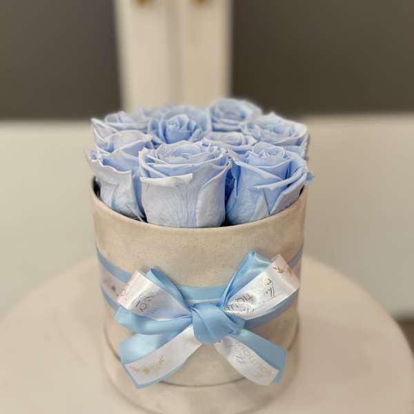 Blue roses arranged in a round hat box with a satin ribbon