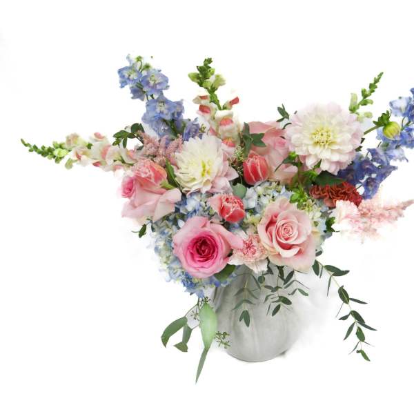 Pink and blue mixed flower arrangement in a white vase