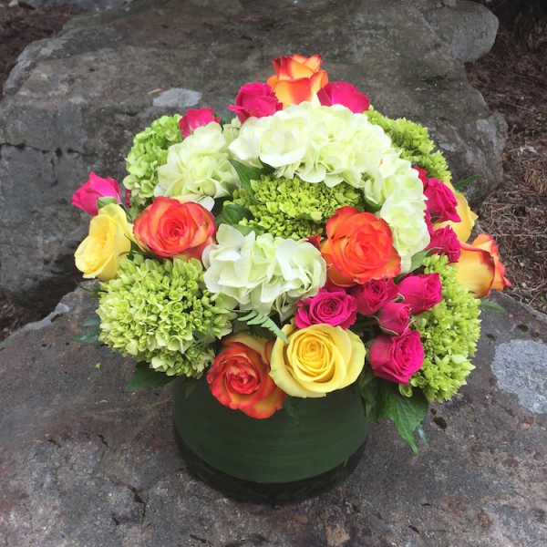 Colorful rose and hydrangea arrangement in a round green vase