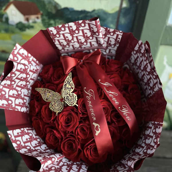 Bouquet of red roses wrapped in patterned burgundy paper with a ribbon