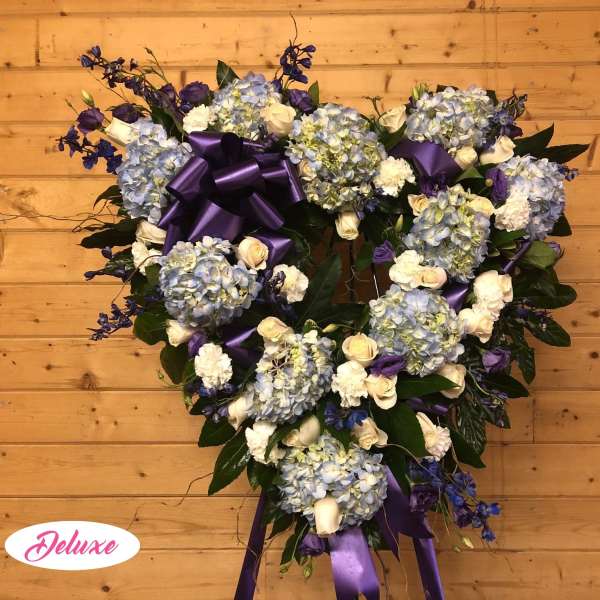 Heart-shaped floral wreath with blue hydrangeas, white roses, and purple ribbon