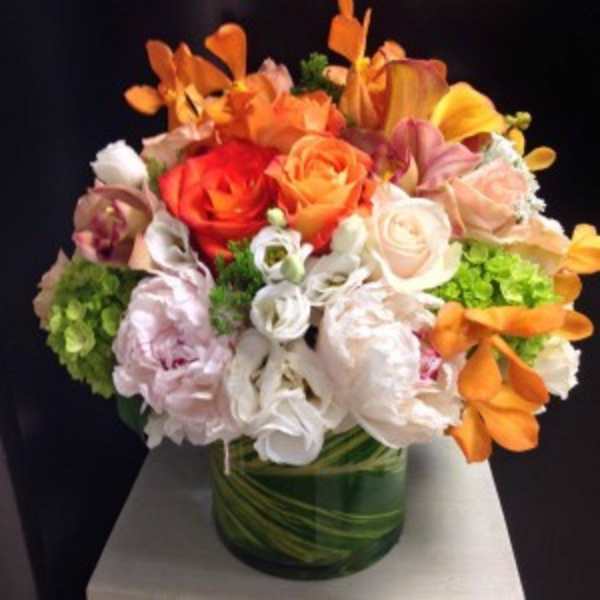 Colorful bouquet of roses and orchids in a green glass vase