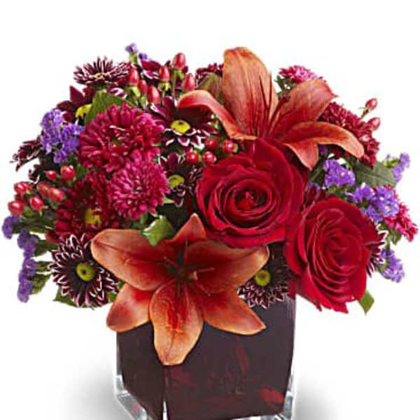 Red roses and orange lilies in a square glass vase